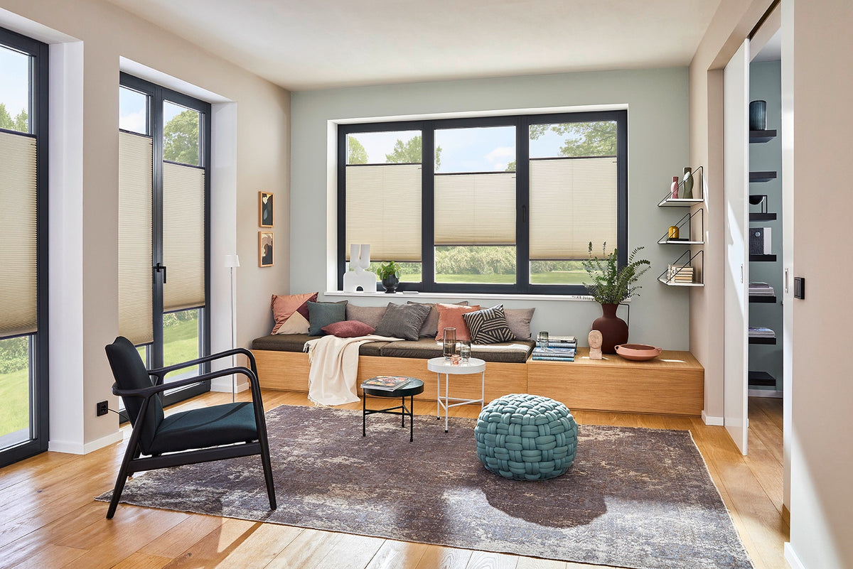 Helles Wohnzimmer mit cremefarbenen DUETTE® Wabenplissees und Sitzbank am Fenster